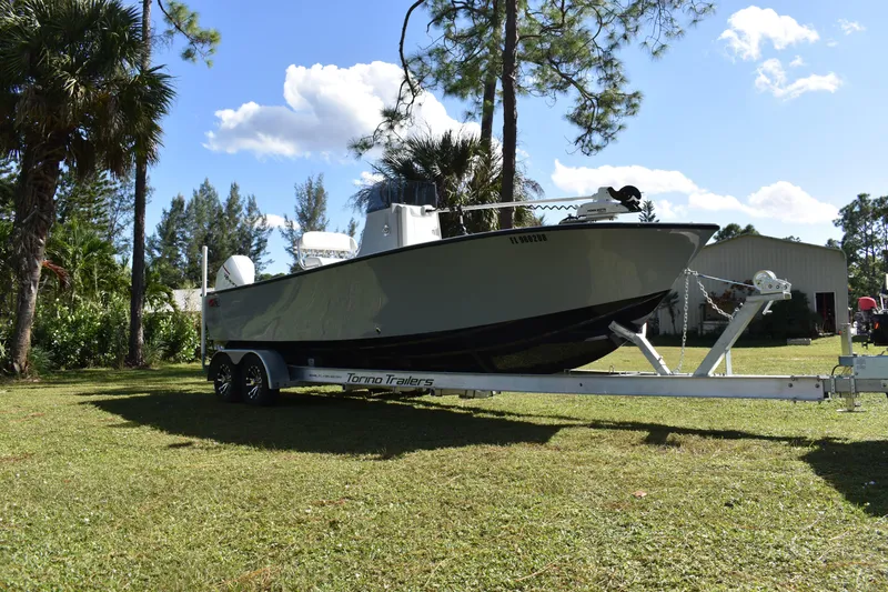 Slide: The Image of 2025 Latitude Tournament Boats 25 on trailer with powerful outboard motor in a wooded area. - 10
