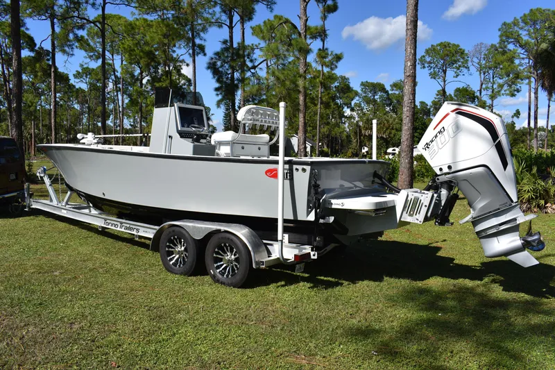 Slide: The Image of 2025 Latitude Tournament Boats 25 on trailer, parked on grass with trees in background. - 5