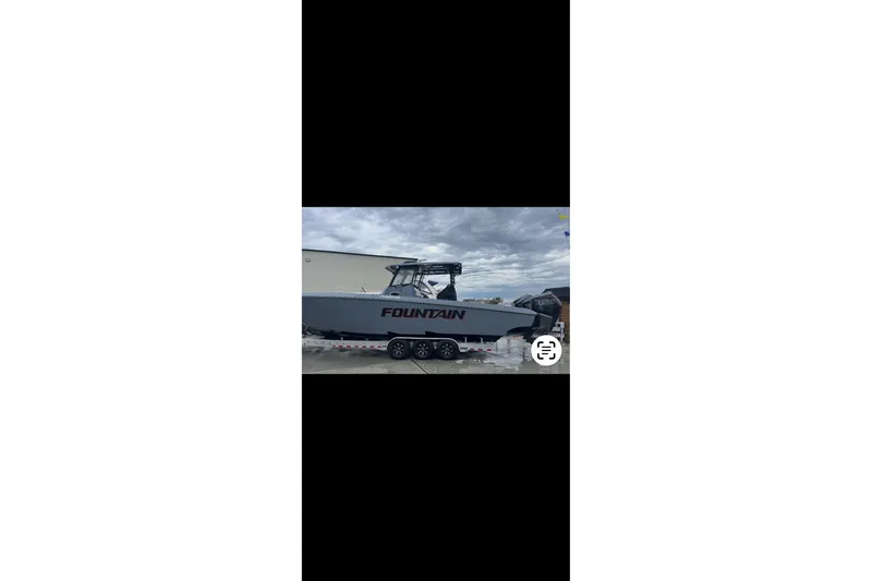 Slide: The Image of 2024 Fountain 38 SC boat on trailer, parked outdoors under cloudy sky. - 6