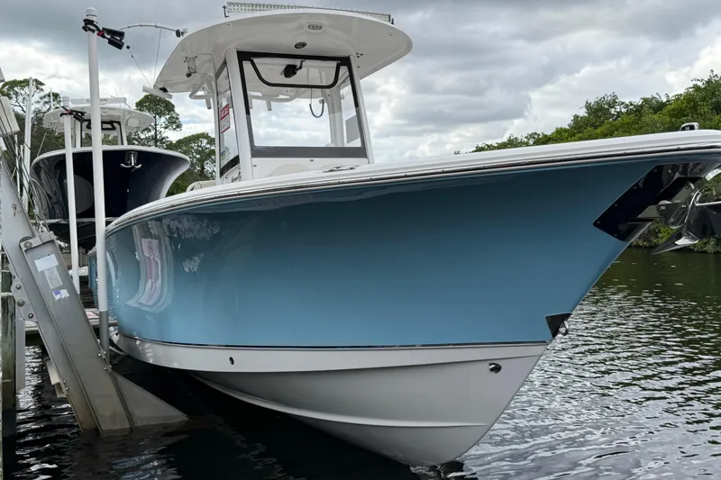 The Image of 2019 Sea Hunt Gamefish 27 boat docked on water, showcasing sleek blue hull design. - 0