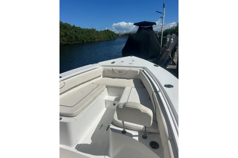 Slide: The Image of 2019 Sea Hunt Gamefish 27 boat with cushioned seating, docked by a scenic waterway. - 11