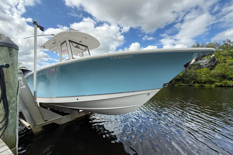 Slide: The Image of 2019 Sea Hunt Gamefish 27 boat on lift, blue hull, under cloudy sky. - 14