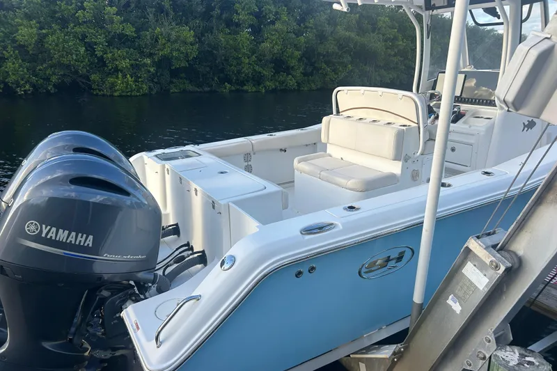 Slide: The Image of 2019 Sea Hunt Gamefish 27 boat with Yamaha engines, docked by lush greenery. - 3