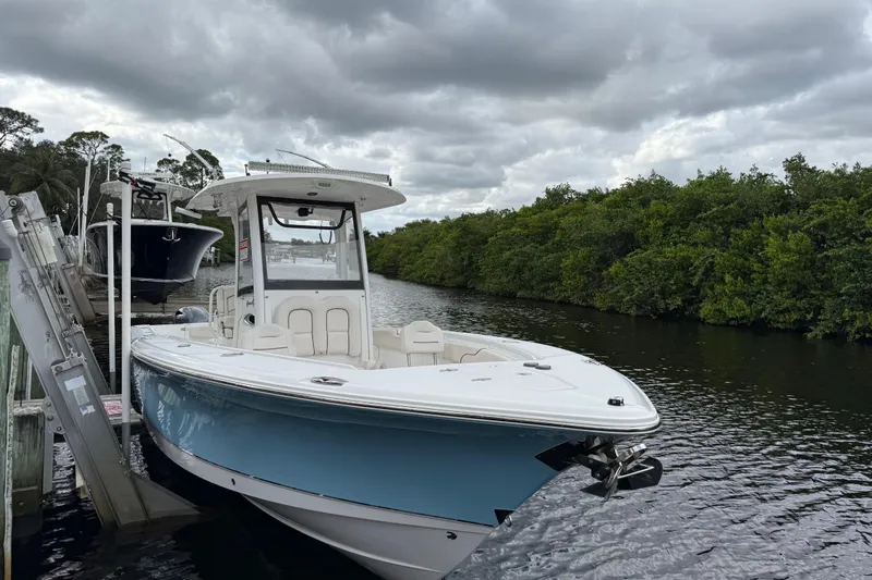 Slide: The Image of 2019 Sea Hunt Gamefish 27 boat docked on a cloudy day by lush greenery. - 6