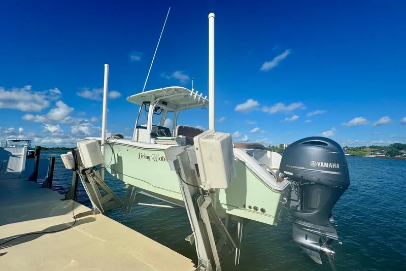 Slide: The Image of 2019 Sea Hunt Ultra 275 SE boat docked with Yamaha engine, under clear blue sky. - 14