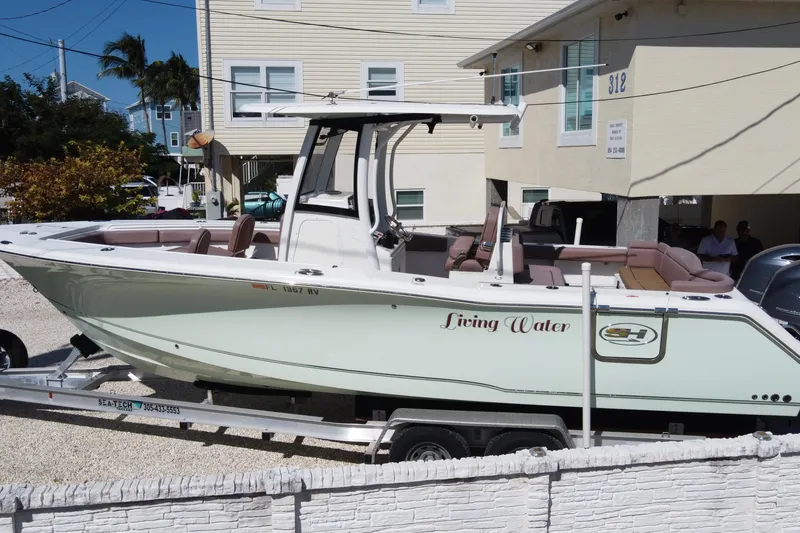 Slide: The Image of 2019 Sea Hunt Ultra 275 SE boat on trailer, labeled "Living Water," parked near a building. - 3