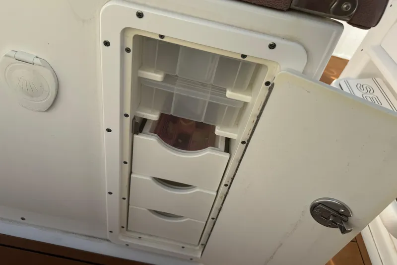 Slide: The Image of 2019 Sea Hunt Ultra 275 SE storage compartment with open door and visible drawers. - 34