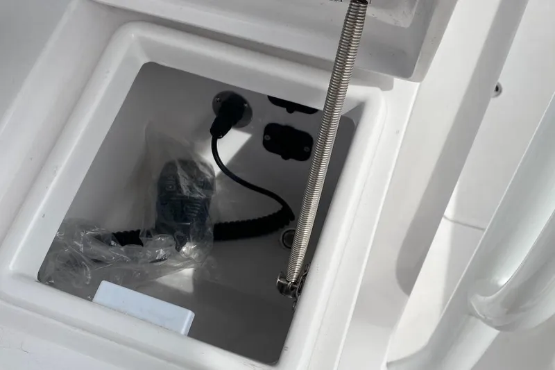 Slide: The Image of Storage compartment on a 2023 Jupiter 32 boat, featuring coiled cable and accessories. - 13
