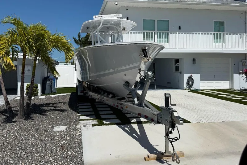 Slide: The Image of 2023 Jupiter 32 boat on trailer in driveway, near palm trees and modern house. - 20
