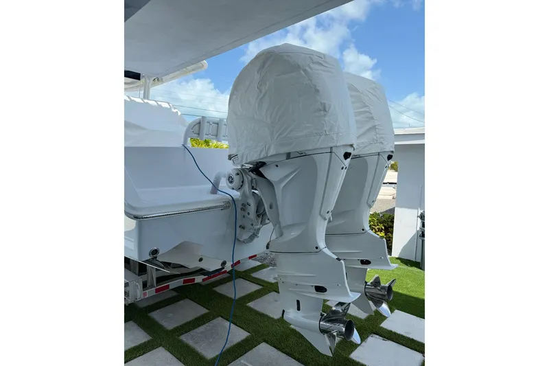 Slide: The Image of 2023 Jupiter 32 boat with dual outboard engines covered, parked on a trailer. - 21