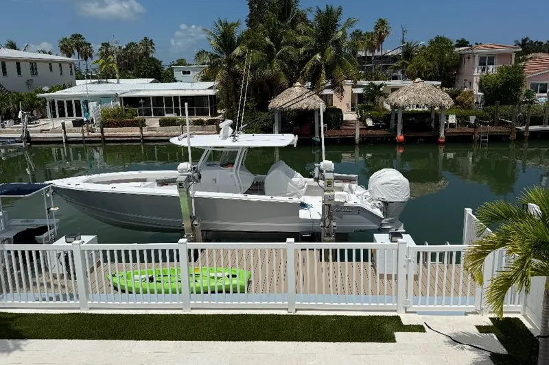 Slide: The Image of 2023 Jupiter 32 boat docked by waterfront homes with palm trees and clear skies. - 24