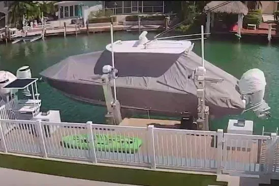 Slide: The Image of Covered 2023 Jupiter 32 boat docked by waterfront with white fence and green kayak. - 25