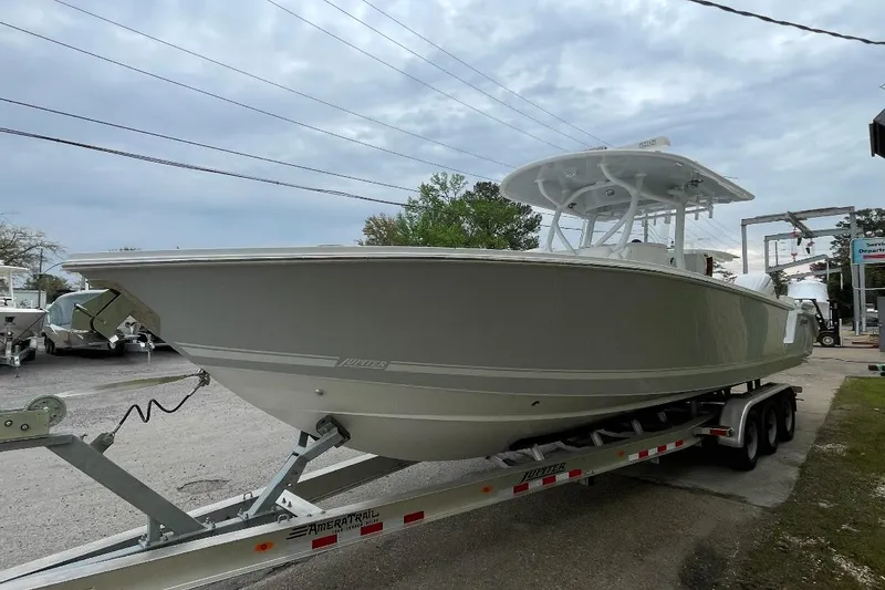 Slide: The Image of 2023 Jupiter 32 boat on trailer, parked outdoors under cloudy sky. - 7