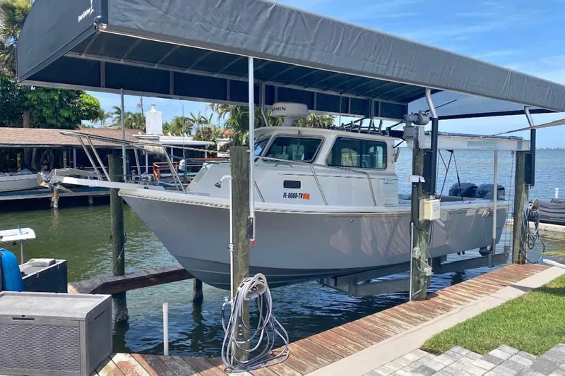 The Image of 2024 Parker 2820 XLD Sport Cabin boat docked under a canopy by the water. - 0