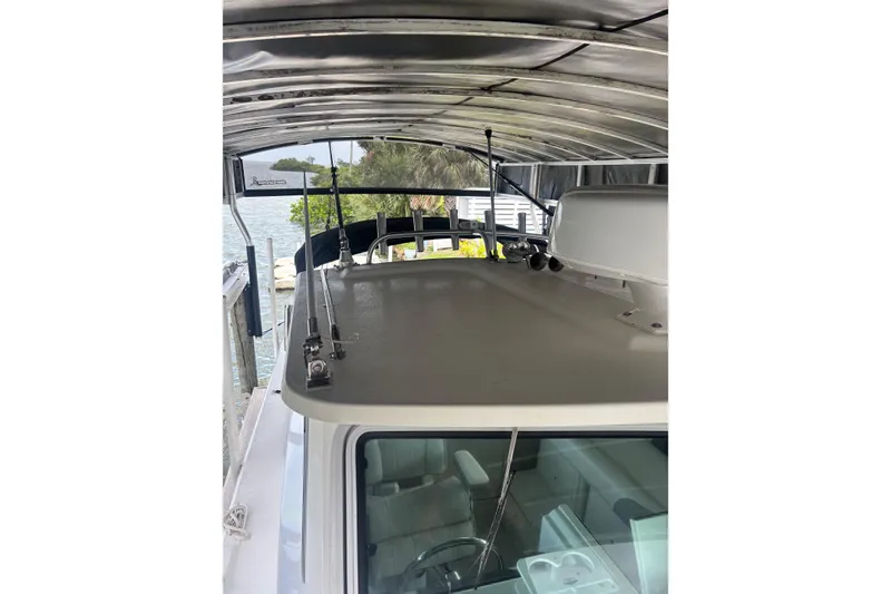Slide: The Image of 2024 Parker 2820 XLD Sport Cabin boat under a metal canopy by the water. - 19