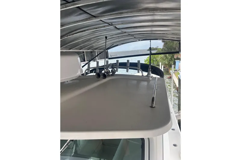 Slide: The Image of 2024 Parker 2820 XLD Sport Cabin boat under a metal canopy by the water. - 20