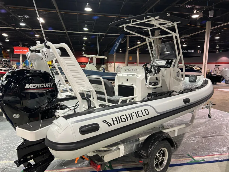 Slide: The Image of 2025 Highfield Sport 560 boat with Mercury engine on display indoors. - 2