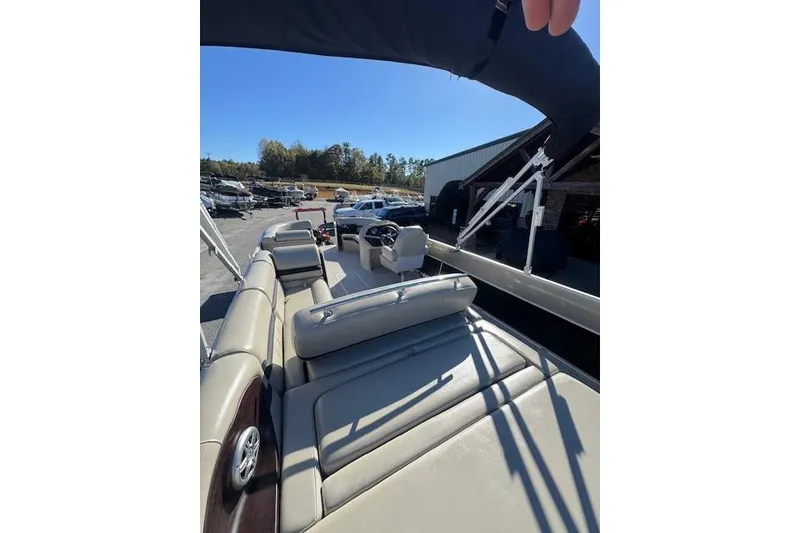 Slide: The Image of 2020 South Bay 200 pontoon boat with beige seating and canopy, parked outdoors. - 10