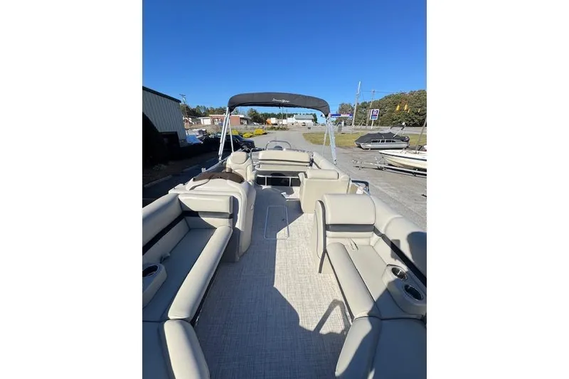 Slide: The Image of 2020 South Bay 200 pontoon boat with spacious seating and canopy, parked outdoors. - 7