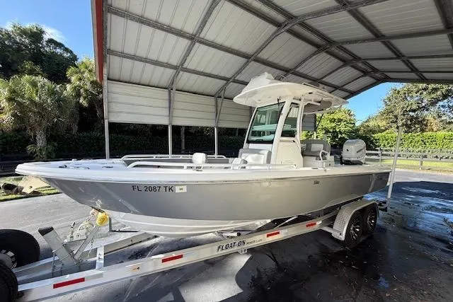 The Image of 2023 Everglades 253 Center Console boat on trailer under a metal canopy. - 0