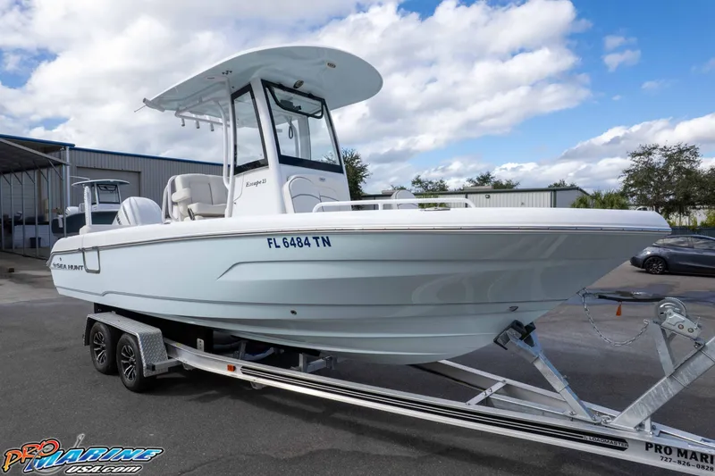 Slide: The Image of 2023 Sea Hunt Escape 23 boat on trailer, parked outdoors under cloudy sky. - 14