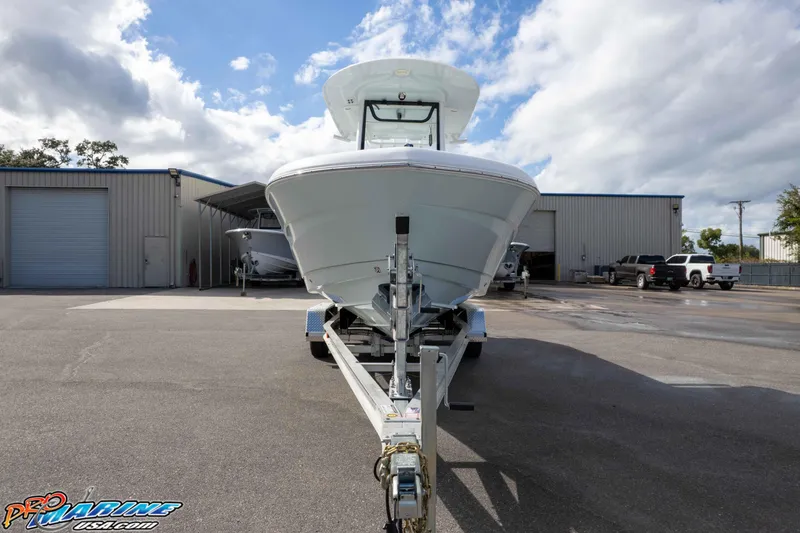 Slide: The Image of 2023 Sea Hunt Escape 23 boat on trailer in industrial lot under cloudy sky. - 17