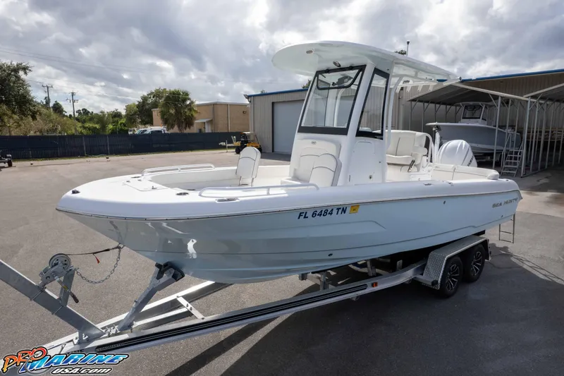 Slide: The Image of 2023 Sea Hunt Escape 23 boat on trailer, parked outdoors under cloudy sky. - 2