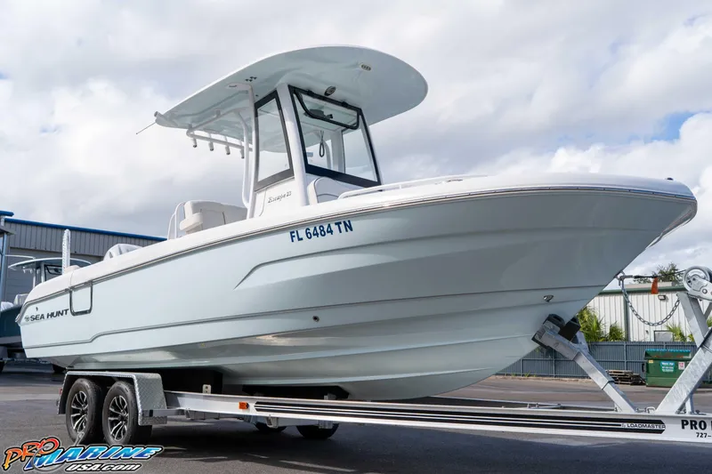 Slide: The Image of 2023 Sea Hunt Escape 23 boat on trailer, displayed outdoors under cloudy sky. - 31