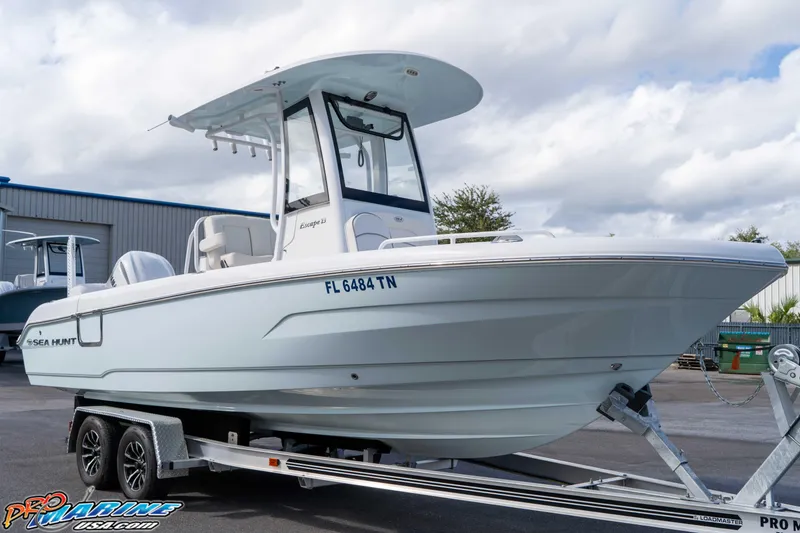 Slide: The Image of 2023 Sea Hunt Escape 23 boat on trailer, displayed outdoors under cloudy sky. - 32