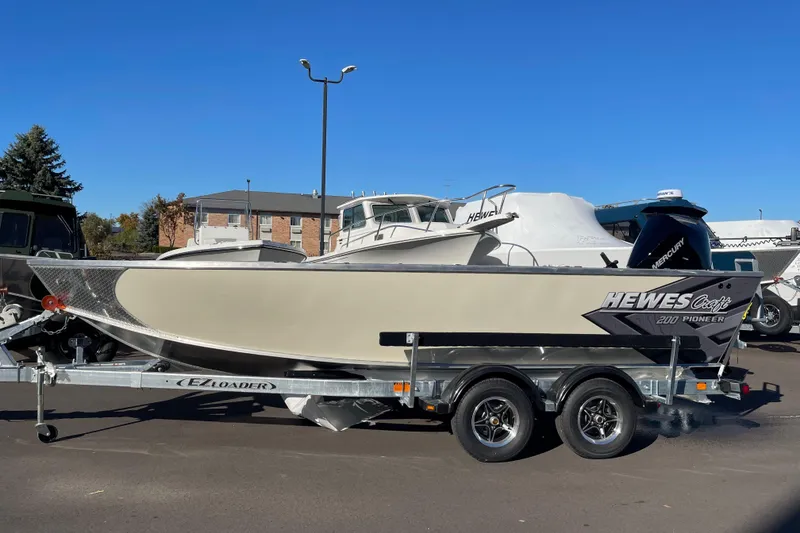 Slide: The Image of 2026 Hewescraft 200 Pioneer boat on trailer, parked outdoors under clear blue sky. - 22