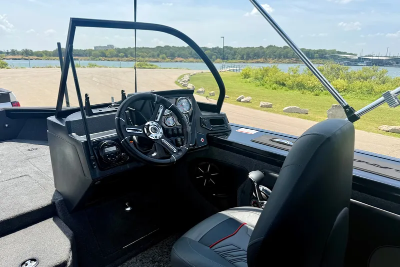 Slide: The Image of 2026 Tracker Targa V-19 WT boat interior with steering wheel and dashboard, near a scenic lake. - 8