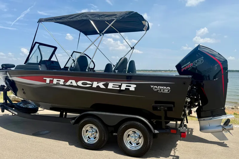 Slide: The Image of 2026 Tracker Targa V-19 WT boat with canopy, parked by a lake. - 18