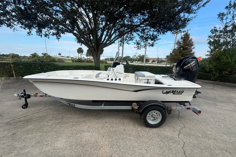 Slide: The Image of 2026 Mako Pro Skiff 15 CC boat on trailer, parked outdoors under a tree. - 0