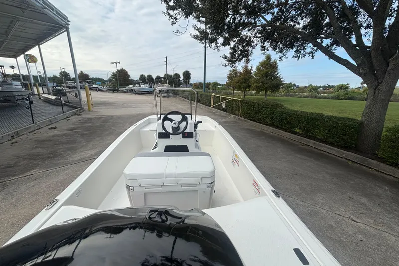 Slide: The Image of 2026 Mako Pro Skiff 15 CC boat parked outdoors, showcasing steering console and seating. - 3