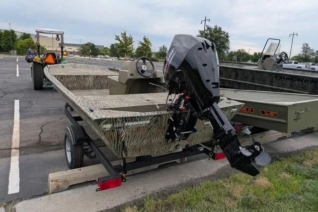 Slide: The Image of 2026 Tracker Grizzly 1648 SC boat on trailer, parked outdoors, featuring camouflage design. - 6