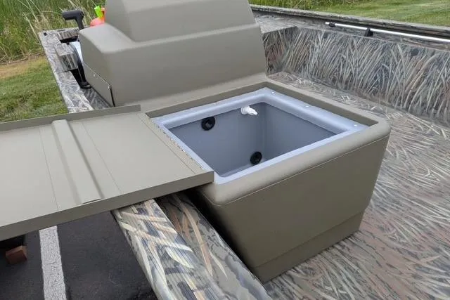 Slide: The Image of 2026 Tracker Grizzly 1648 SC boat with open storage compartment, camo design, and seating area. - 4