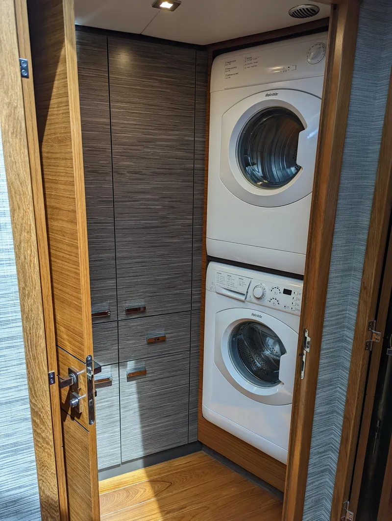 Slide: The Image of 2020 Tiara Yachts F53 Flybridge laundry area with stacked washer and dryer. - 17