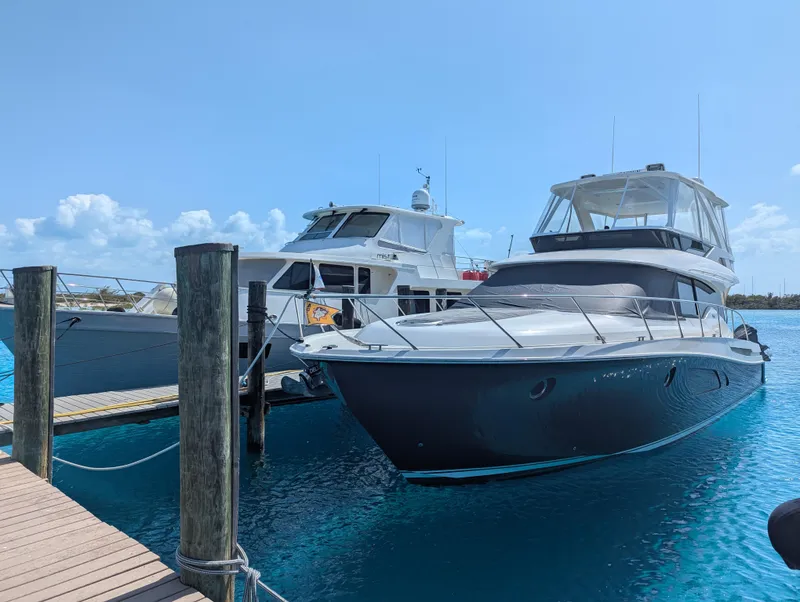 Slide: The Image of 2020 Tiara Yachts F53 Flybridge docked beside another boat in clear blue water. - 2