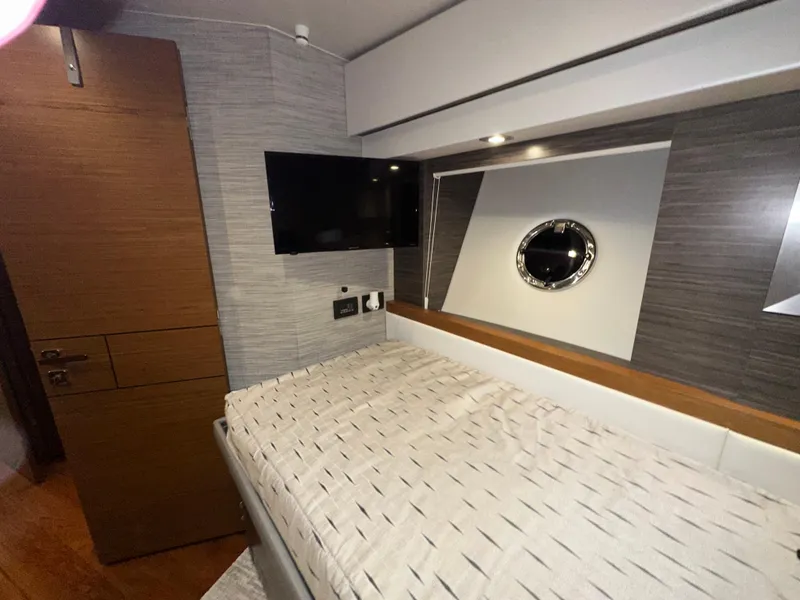 Slide: The Image of 2020 Tiara Yachts F53 Flybridge cabin interior with bed, TV, and porthole window. - 20