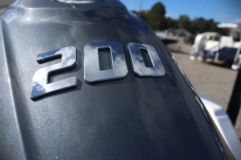 Slide: The Image of Chrome "200" emblem on 2026 Tidewater 220 LXF boat, reflecting sky and clouds. - 5