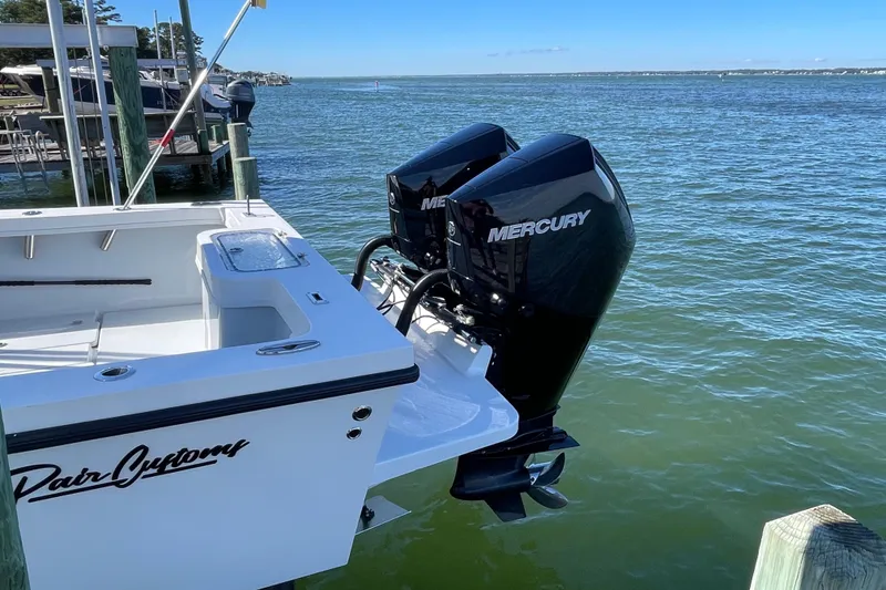 Slide: The Image of 2023 Pair Customs 24 Center Console DV boat with dual Mercury engines docked by the water. - 10