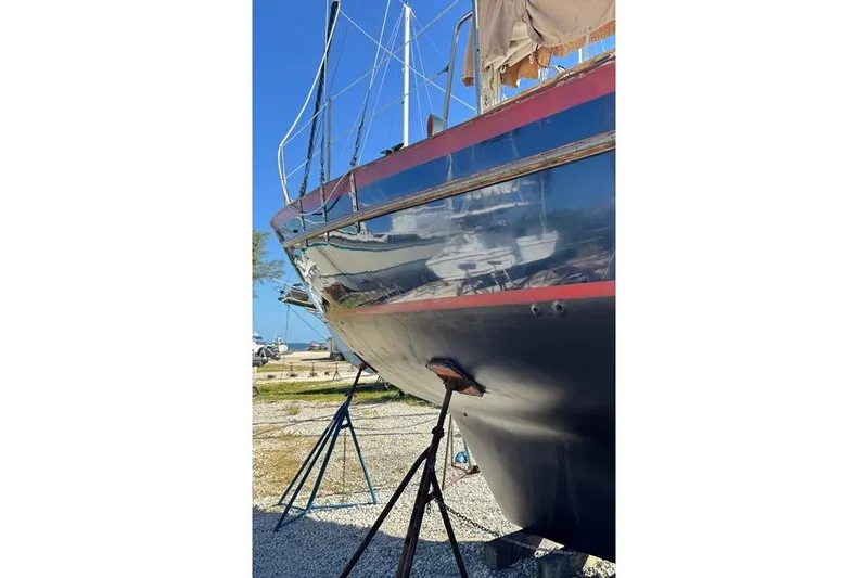 Slide: The Image of 1989 Pacific Seacraft Crealock sailboat on stands, blue hull with red stripe, sunny day. - 12