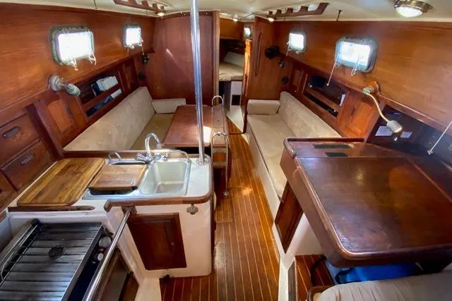 Slide: The Image of 1989 Pacific Seacraft Crealock yacht interior with wooden finish, kitchen, and seating area. - 17