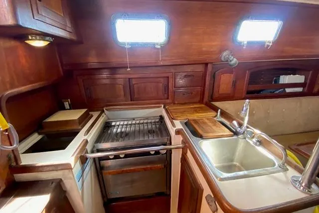Slide: The Image of 1989 Pacific Seacraft Crealock yacht interior kitchen with wooden cabinetry and stainless steel sink. - 18