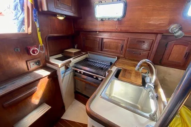 Slide: The Image of 1989 Pacific Seacraft Crealock yacht kitchen with wooden cabinetry, stove, and sink. - 19