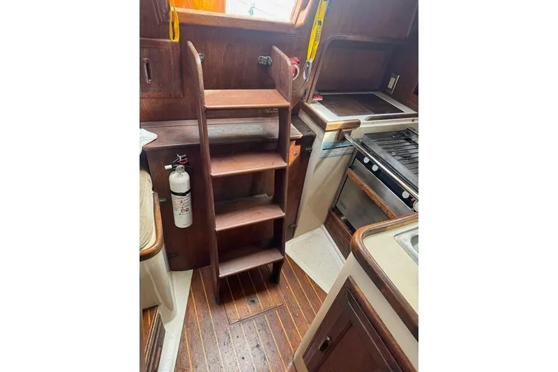 Slide: The Image of 1989 Pacific Seacraft Crealock interior with wooden steps, kitchen area, and fire extinguisher. - 30