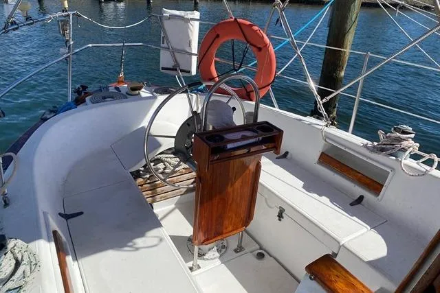 Slide: The Image of 1989 Pacific Seacraft Crealock sailboat cockpit with steering wheel, wooden accents, and life preserver. - 7