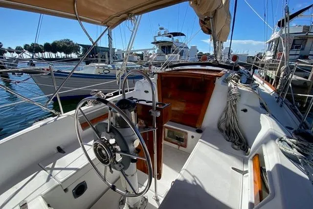 Slide: The Image of 1989 Pacific Seacraft Crealock sailboat cockpit with steering wheel, docked at marina. - 8
