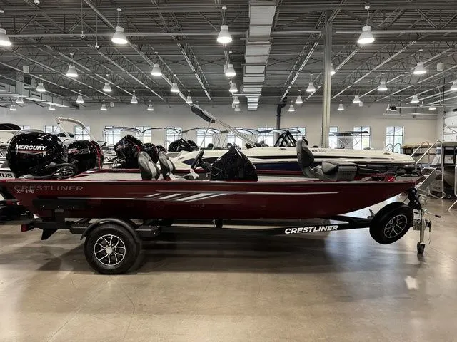 Slide: The Image of 2025 Crestliner XFC 179 boat in showroom, side view, on trailer, with Mercury outboard motor. - 1