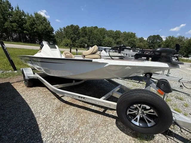 The Image of 2023 Xpress Boats H17C on trailer, parked outdoors, surrounded by trees and gravel. - 1